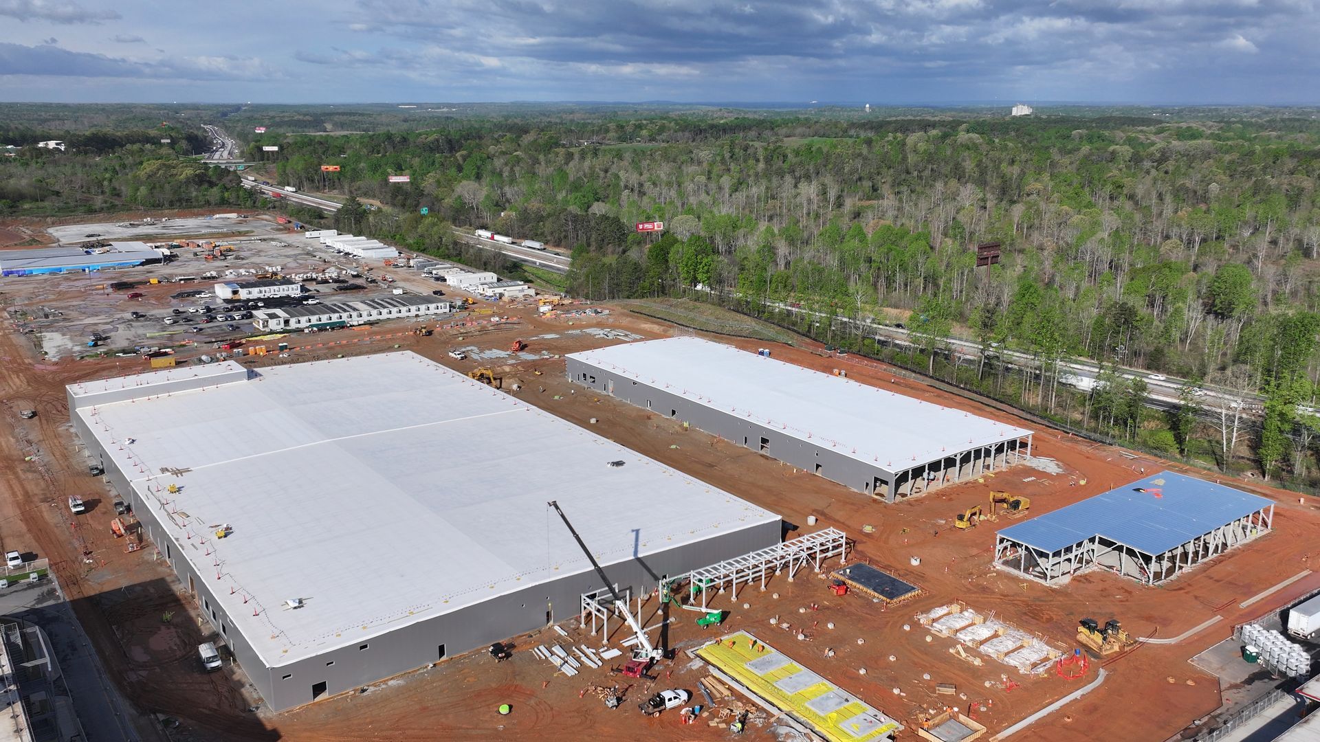 An aerial view of a construction site with a lot of buildings and trees in the background.