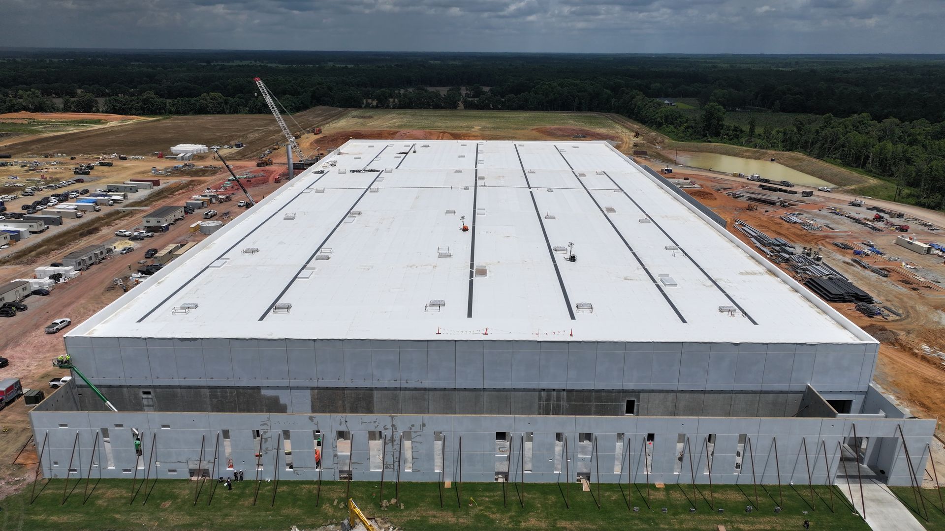 An aerial view of a large building under construction with a white roof.