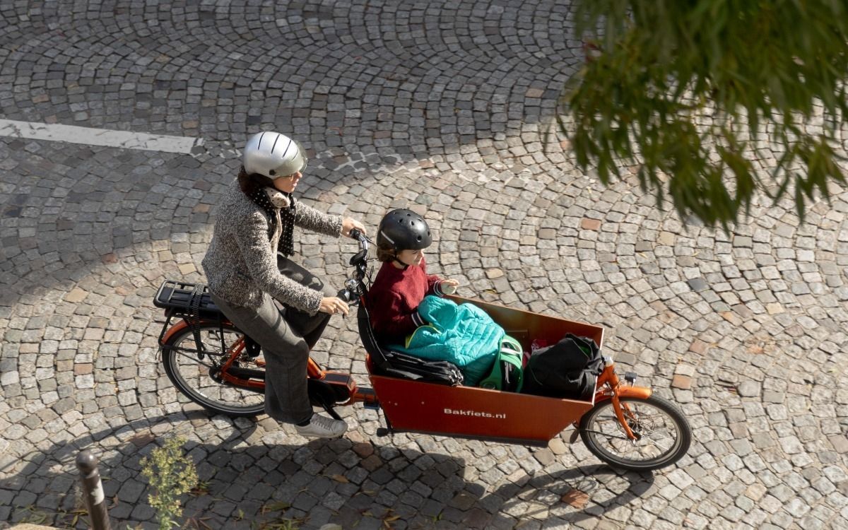 Un homme et une femme regardent un vélo cargo dans un magasin de vélos. L'homme tient le guidon, la femme montre le coffre.