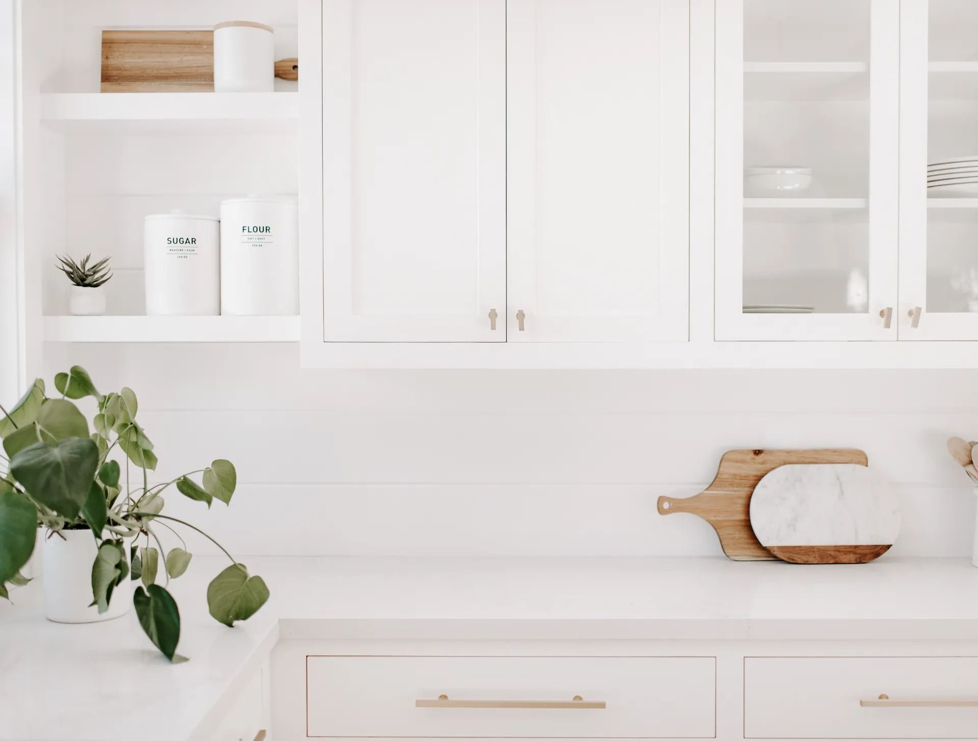 A kitchen with white cabinets and a wooden cutting board on the counter.