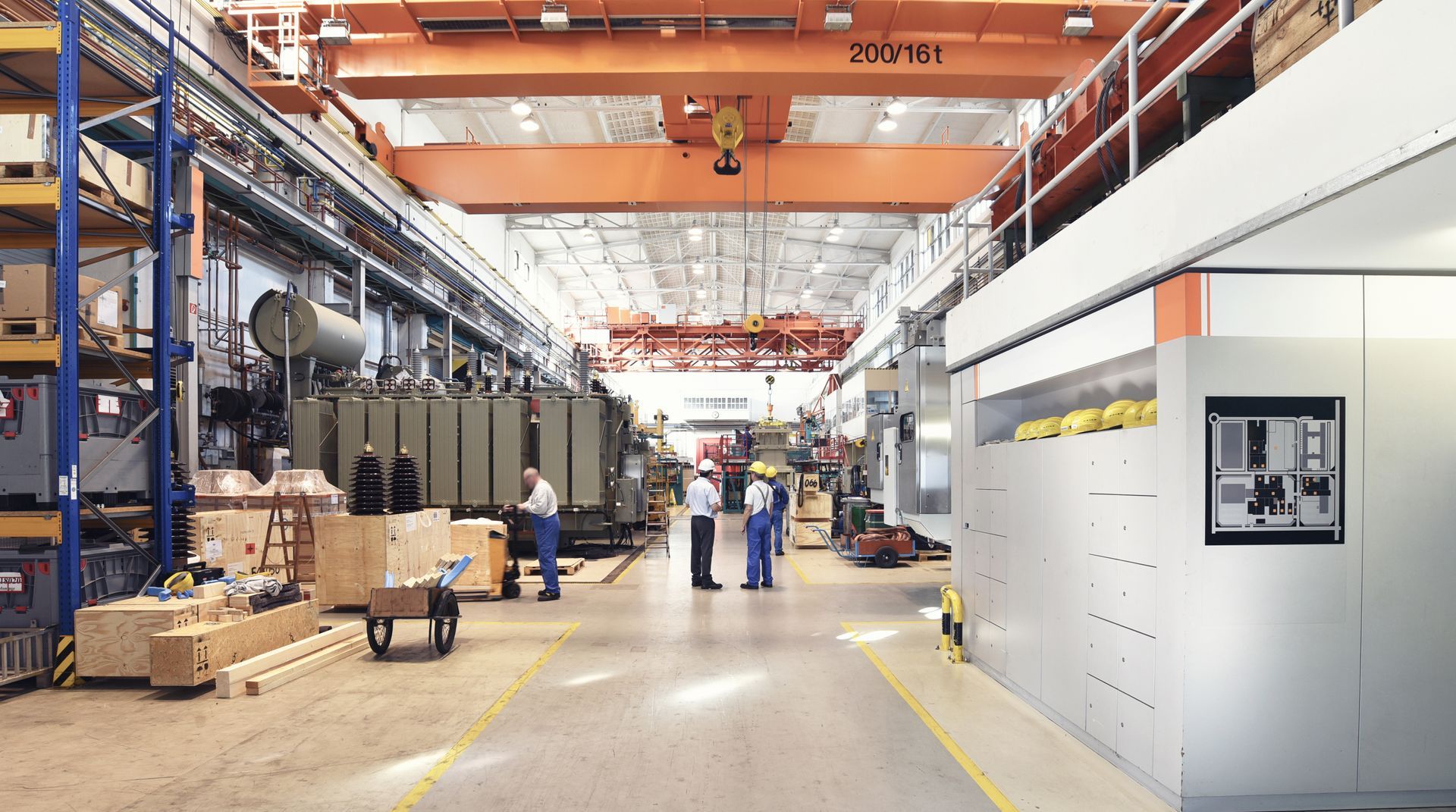 A group of people are standing in a large factory.