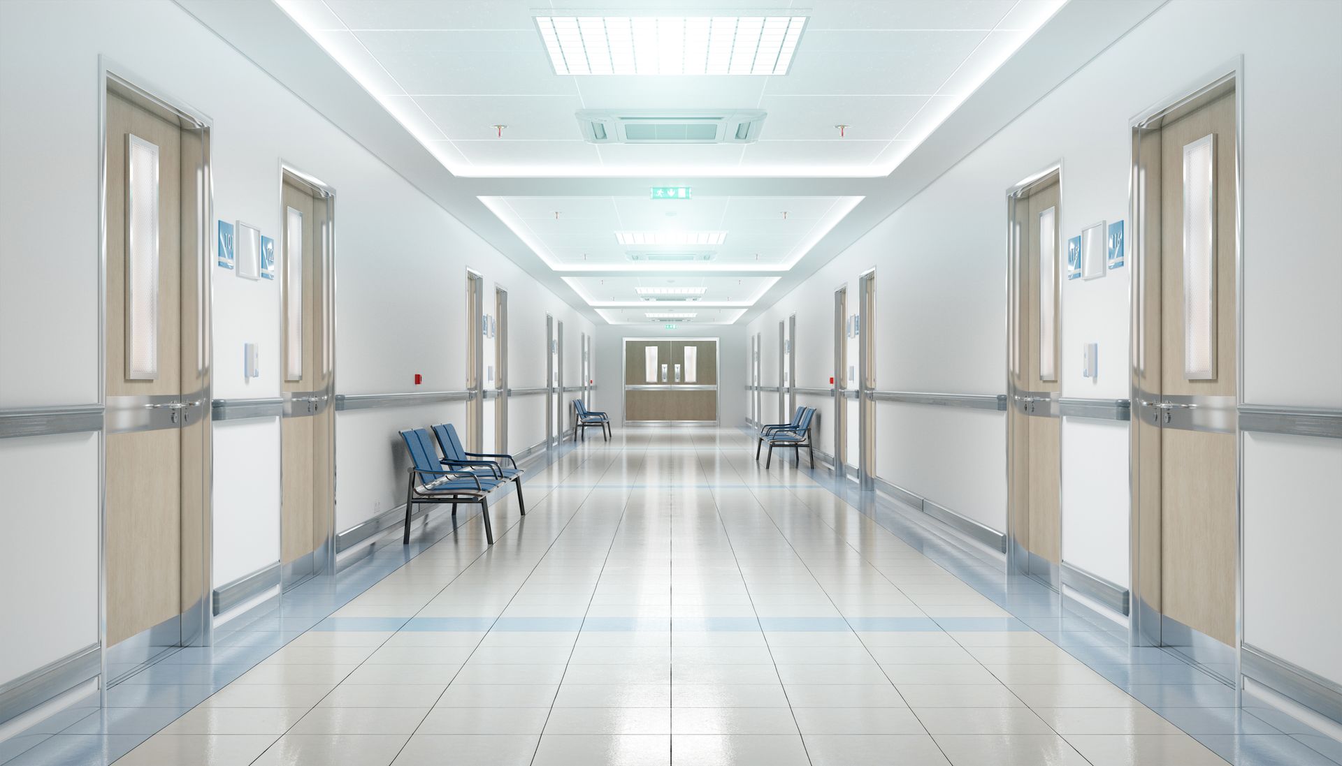 An empty hospital hallway with chairs and doors.