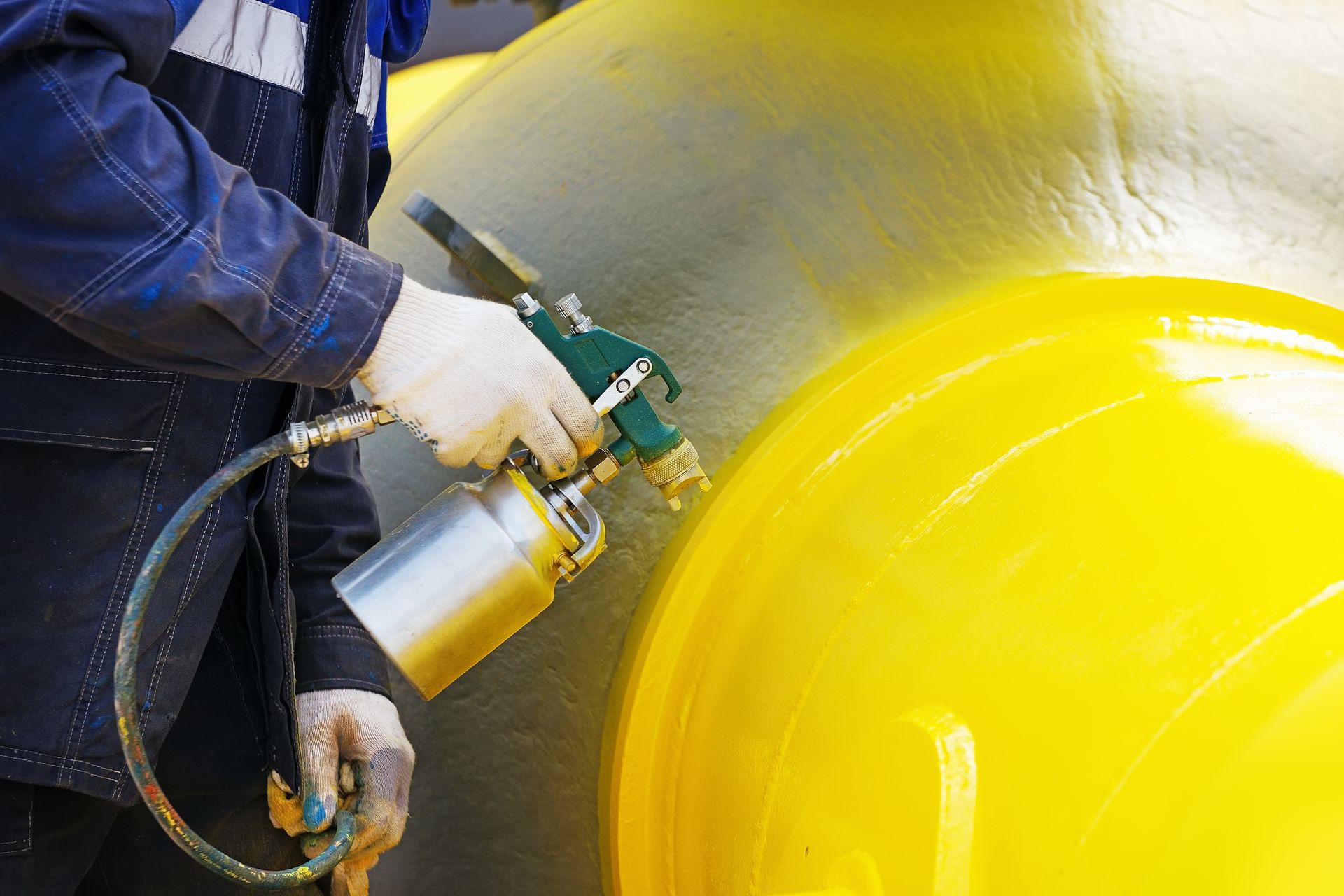 A man is spraying yellow paint on a yellow object.
