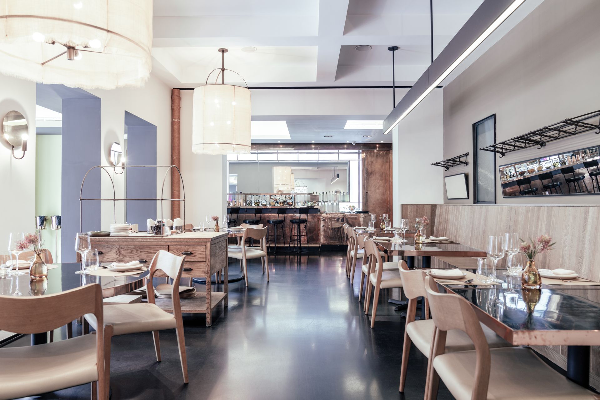 A restaurant with tables and chairs and a bar in the background.