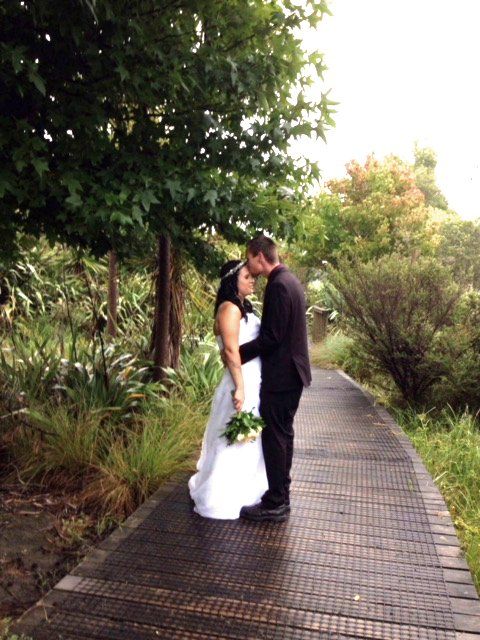 A bride and groom kissing on a wooden walkway