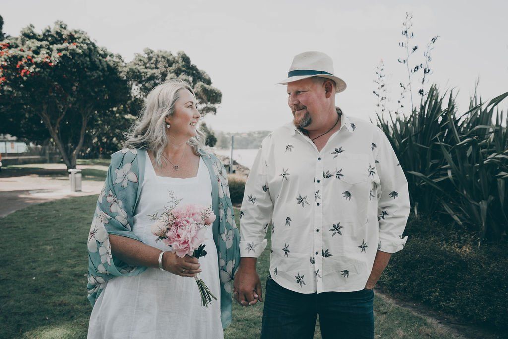 A man and a woman are holding hands and walking in a park.