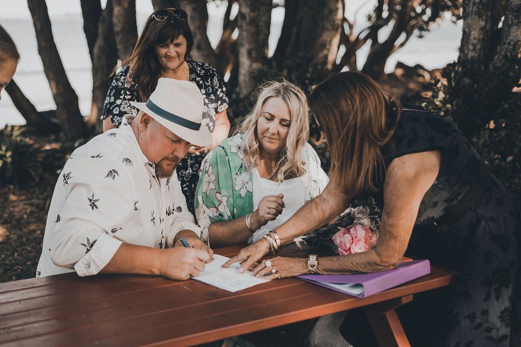 A group of people are sitting at a picnic table signing a document.