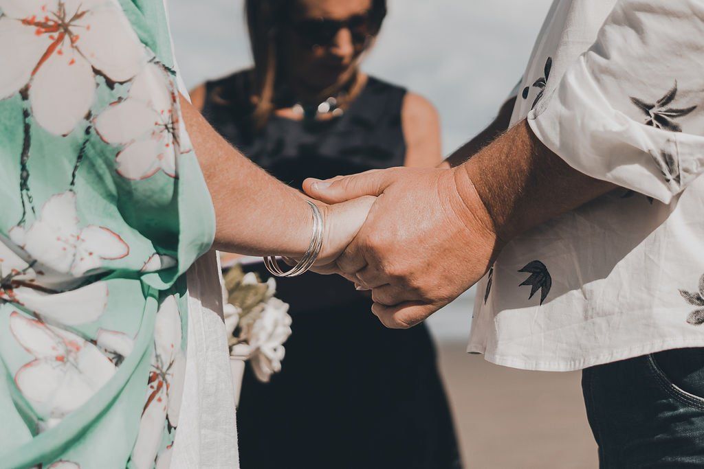 A man and a woman are holding hands during a wedding ceremony.