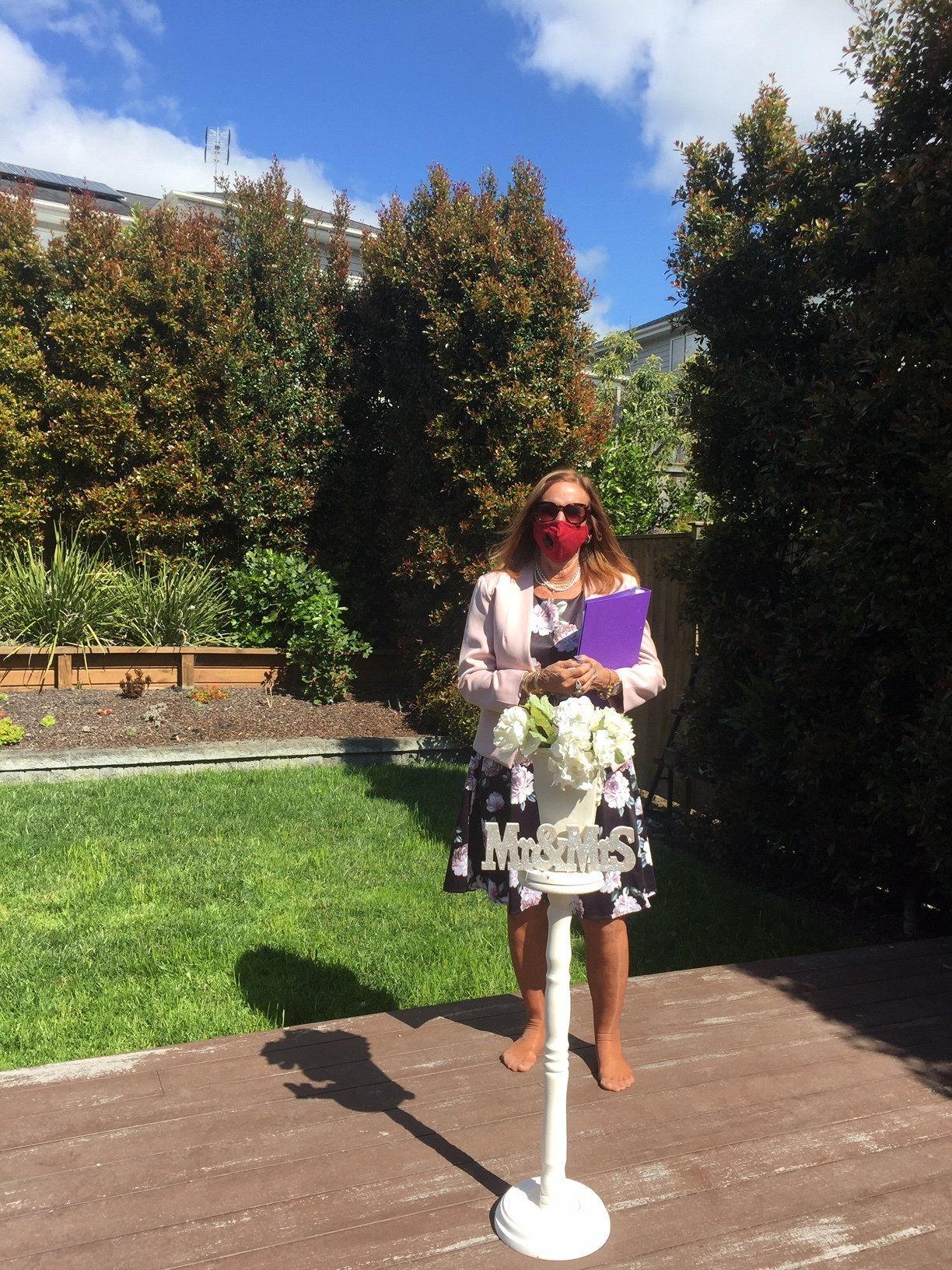 A woman wearing a mask is standing in front of a sign that says welcome.