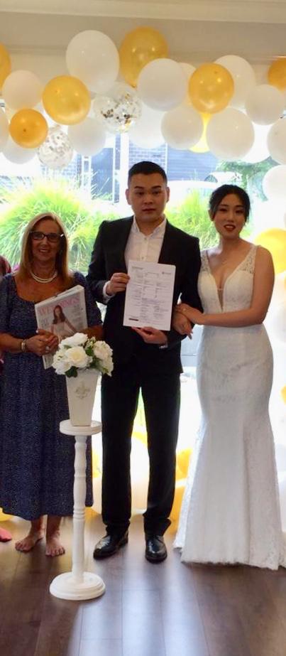 A bride and groom are standing next to each other in a room with balloons.