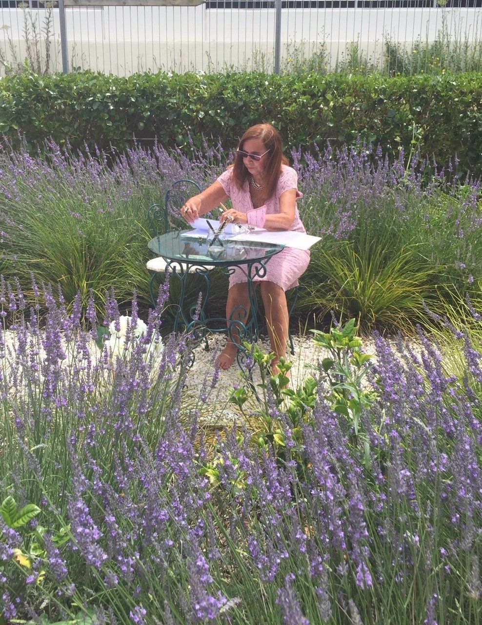 A woman is sitting at a table in a field of lavender flowers.