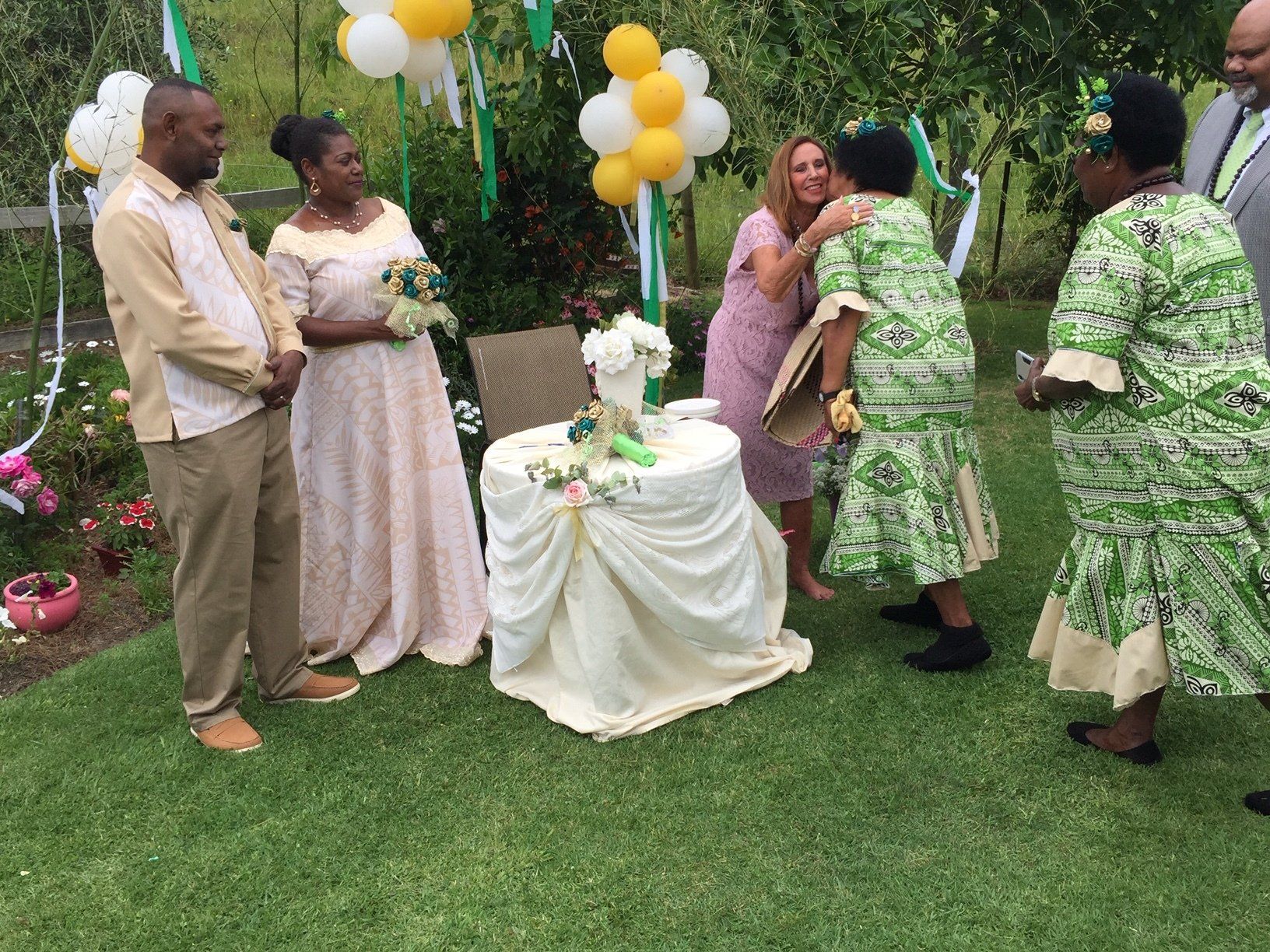 A group of people are standing around a table with balloons on it.