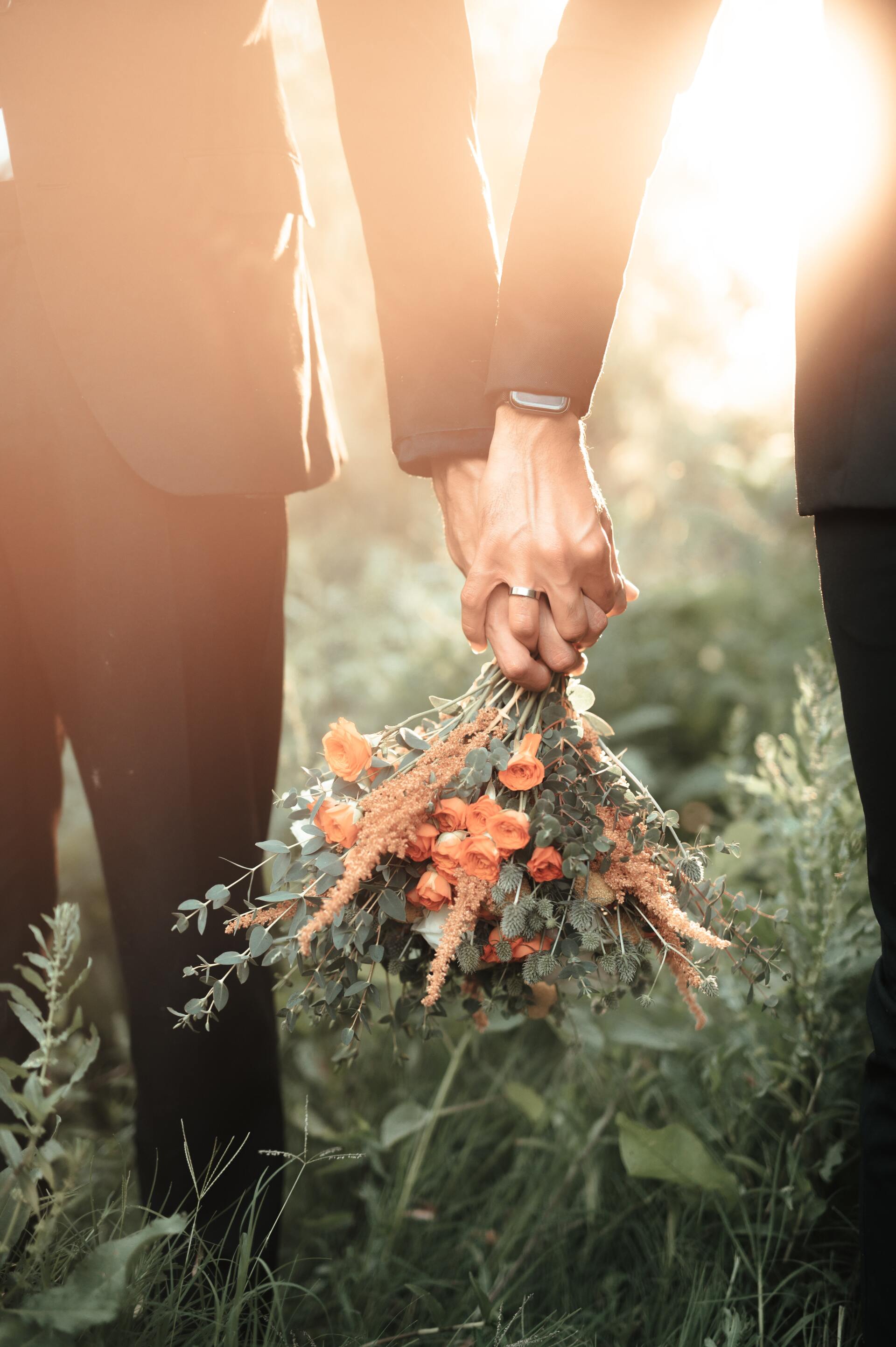 A man and woman are holding hands while holding a bouquet of flowers.