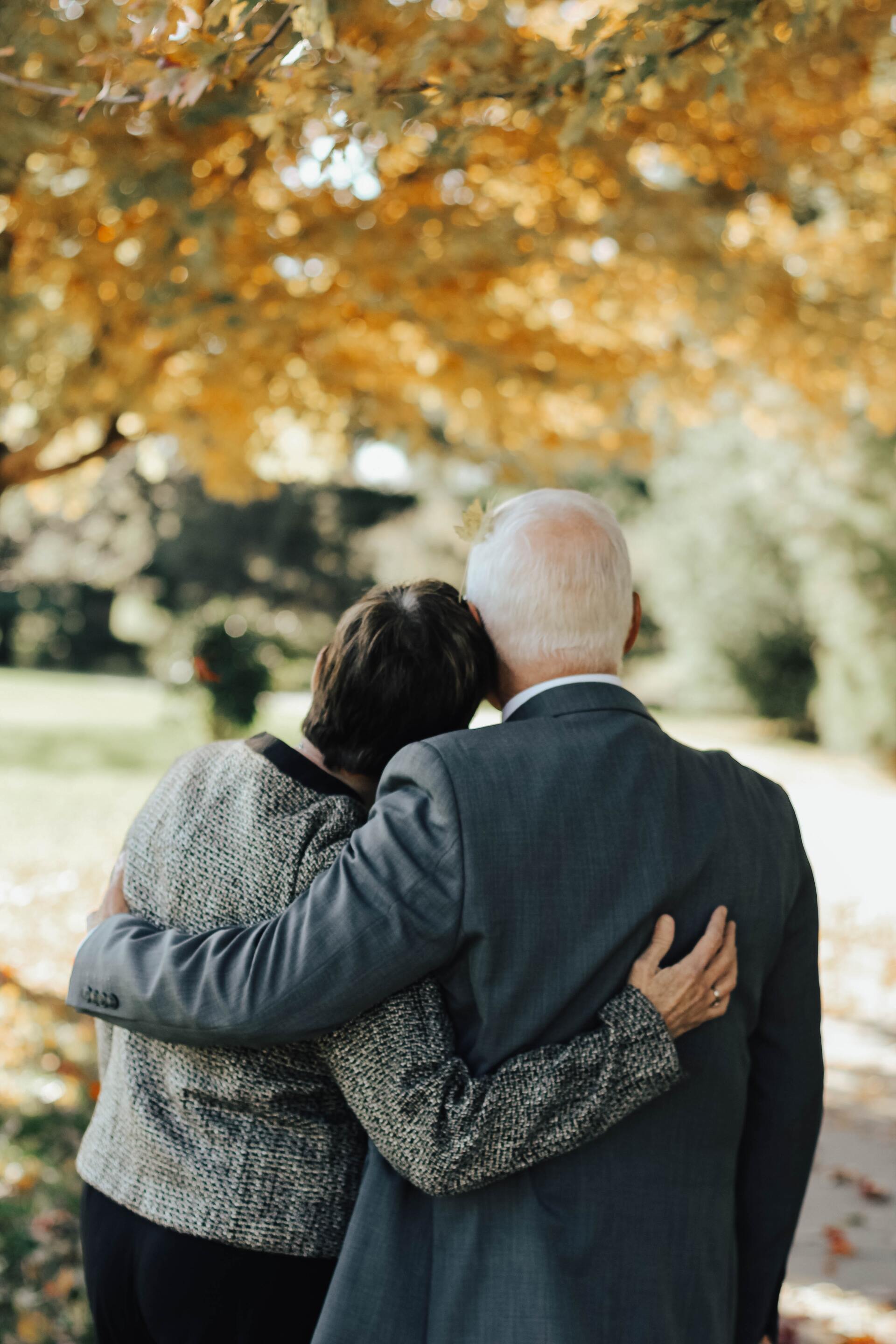 A man and a woman are hugging each other in a park.