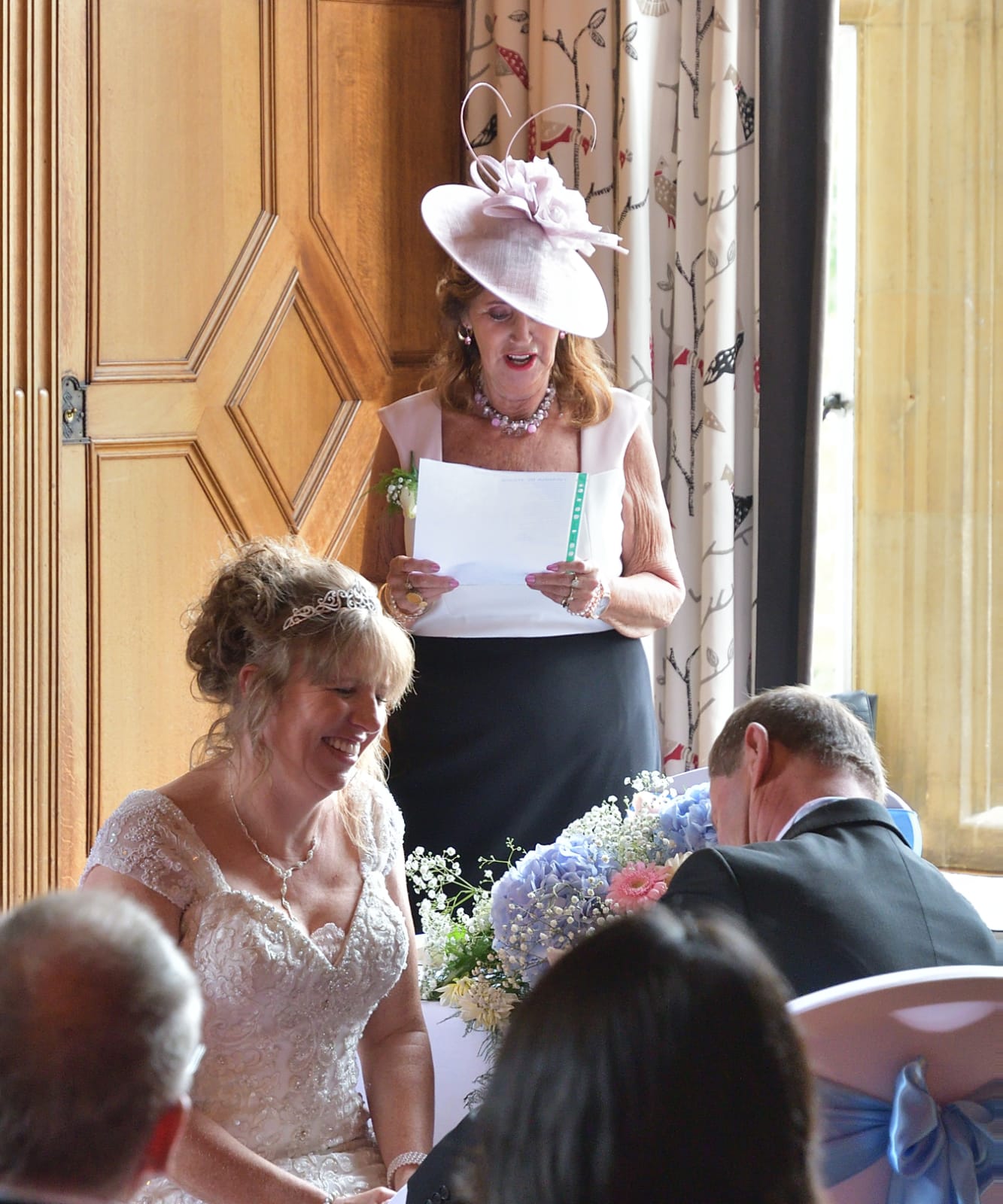 A woman in a hat is giving a speech at a wedding