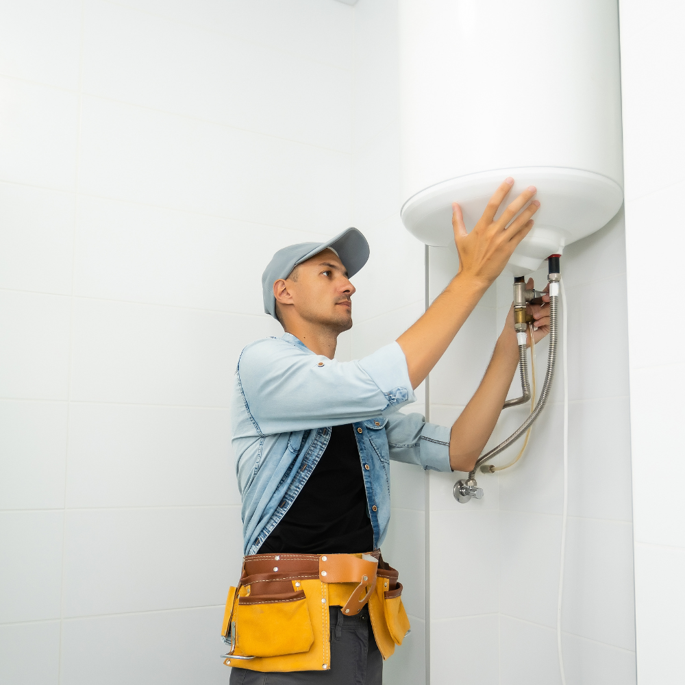 A man is fixing a water heater in a bathroom.