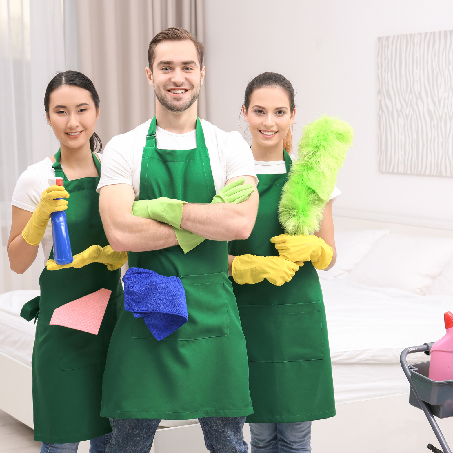 A man and two women are standing next to each other holding cleaning supplies.