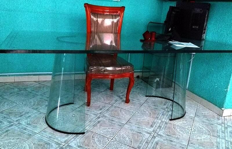 Una mesa de cristal con una silla roja debajo.