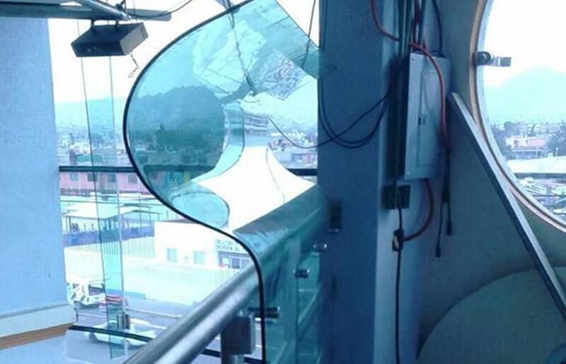 Un balcón con barandilla de cristal y una ventana redonda.