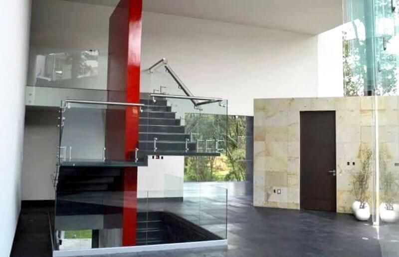 Una escalera en una casa con barandilla de cristal.