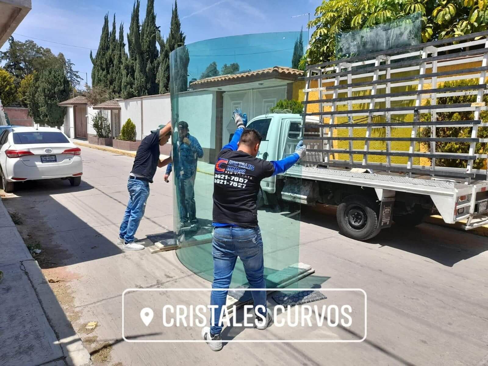 Un grupo de hombres está trabajando en un gran trozo de vidrio delante de un camión.