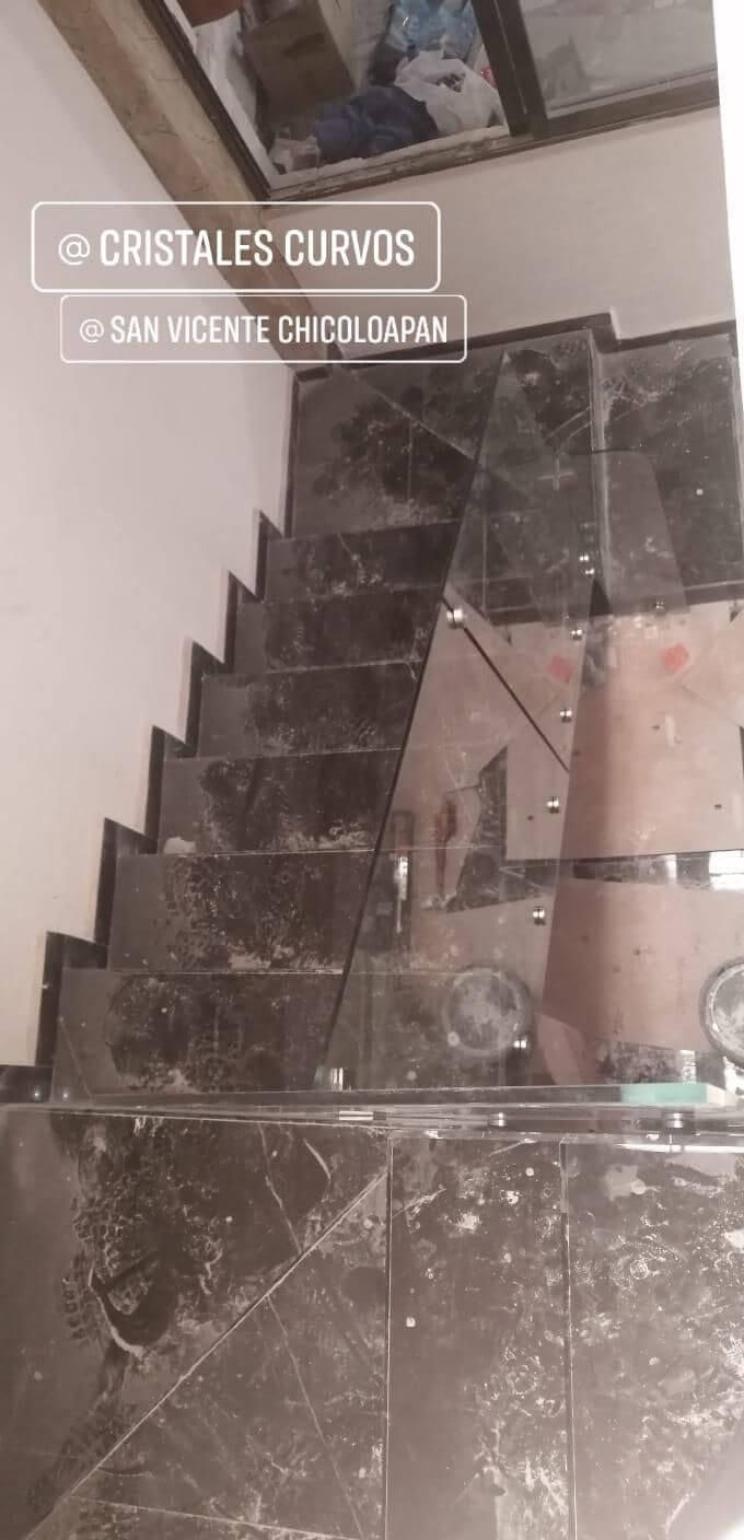 Un primer plano de una escalera con barandilla de cristal.