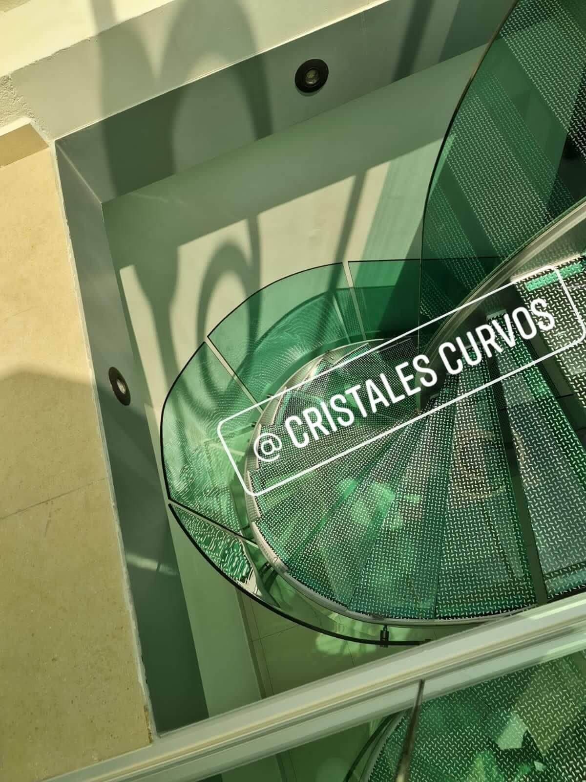 Una escalera de caracol de cristal con un cartel que dice cristales curvos