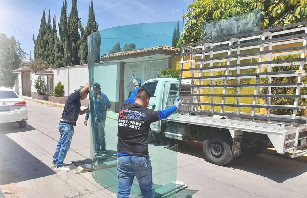 Dos hombres están instalando un gran trozo de vidrio delante de un camión.