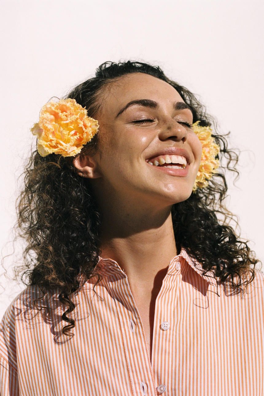 a woman with a flower in her hair is smiling