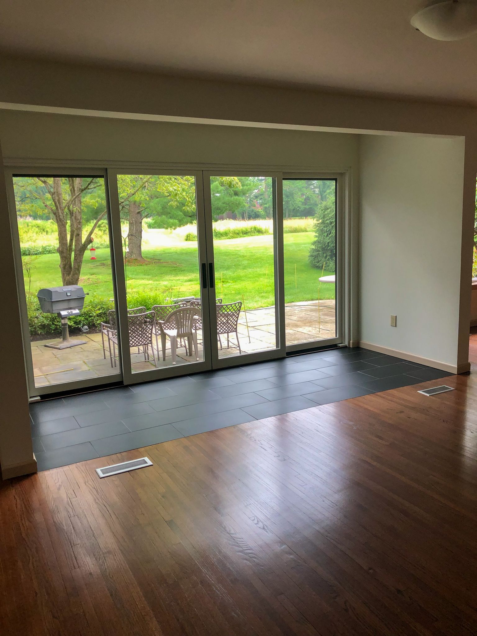 An empty living room with hardwood floors and sliding glass doors.