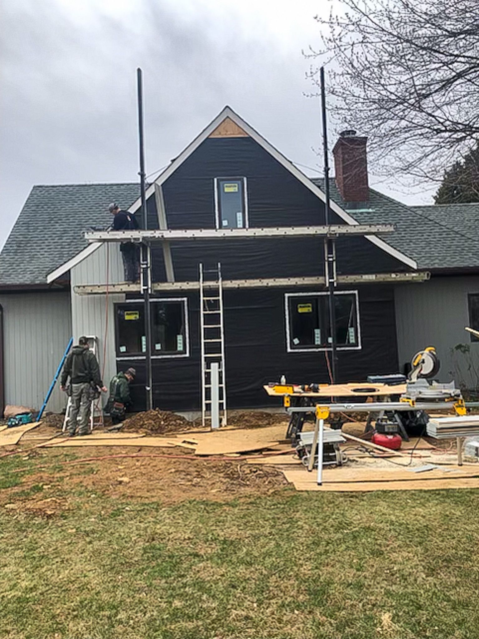 A house is being remodeled with a black siding and white trim.