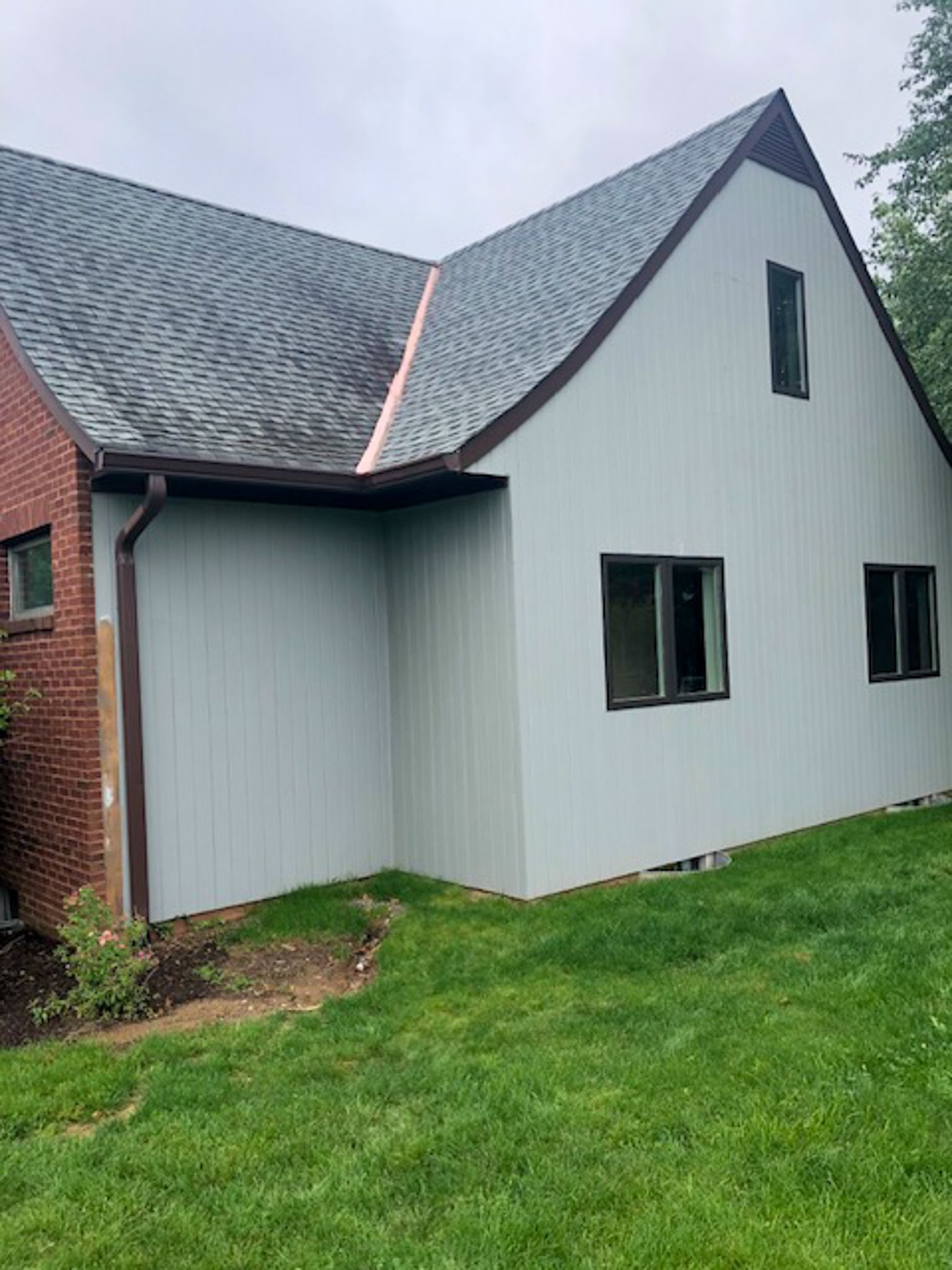 A white house with a brown roof is sitting on top of a lush green field.