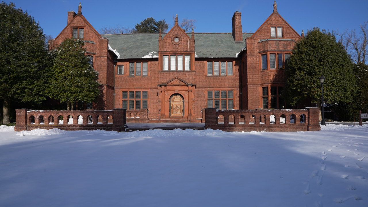 A large brick building with snow on the ground in front of it