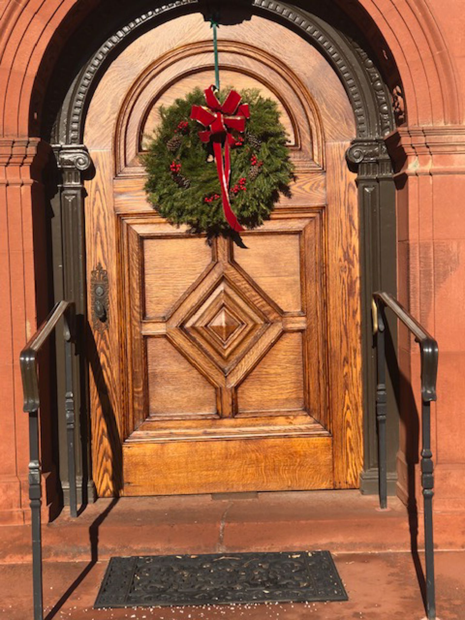 A wooden door with a christmas wreath hanging from it