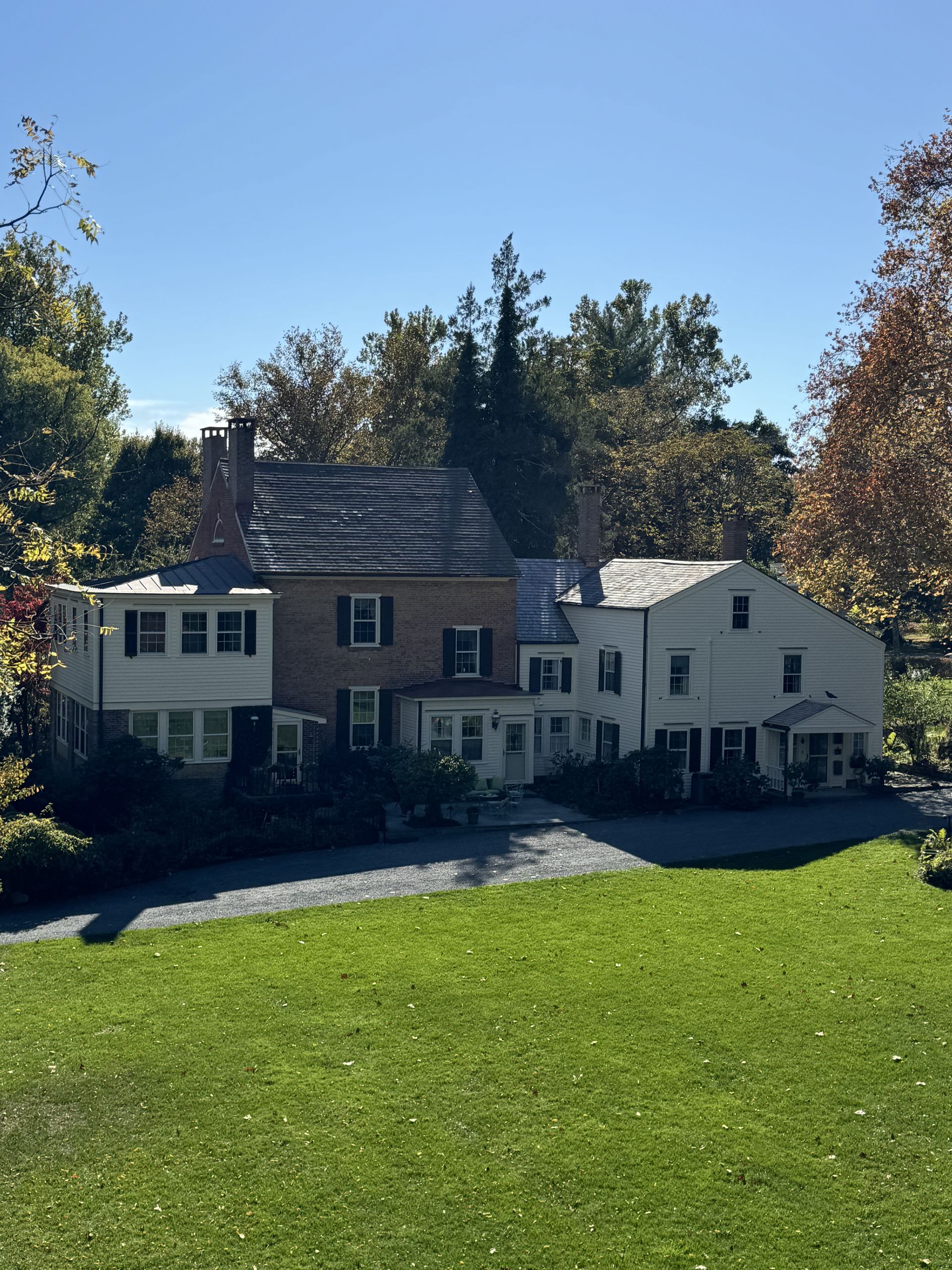 A large house sits in the middle of a lush green field
