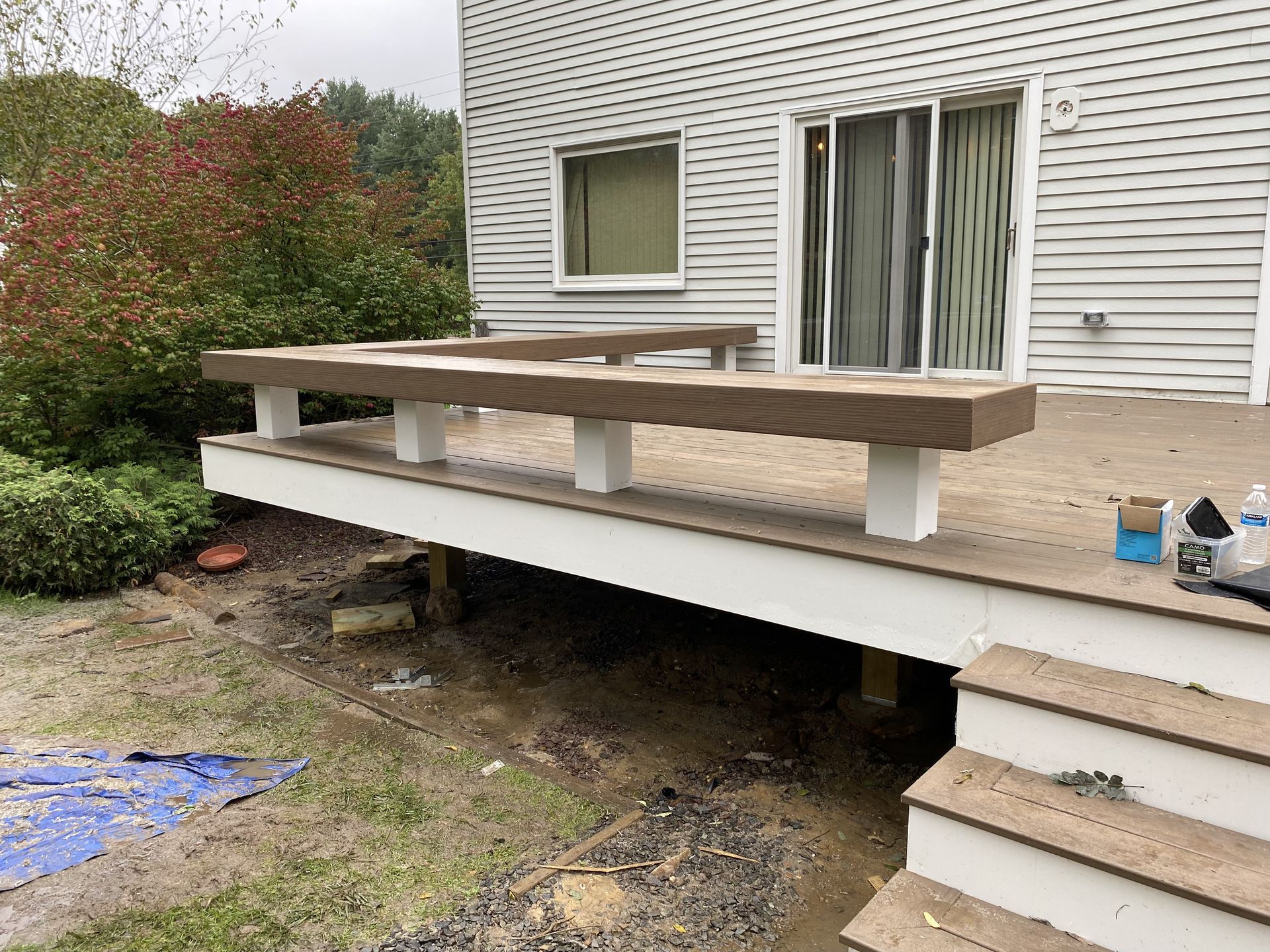 A wooden deck with a bench and stairs in front of a house.