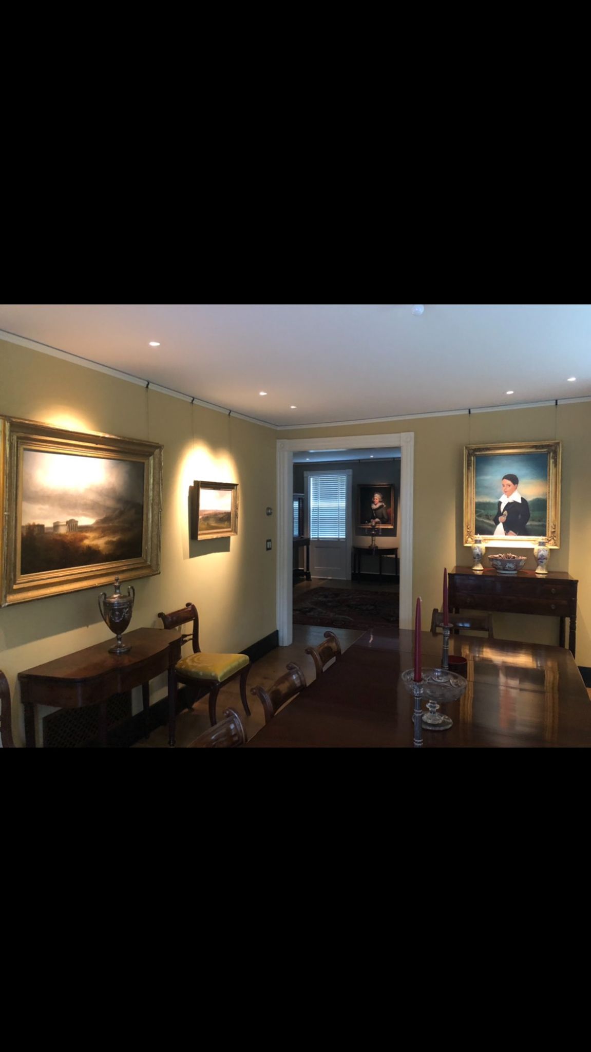 A living room with a table , chairs , and paintings on the wall.