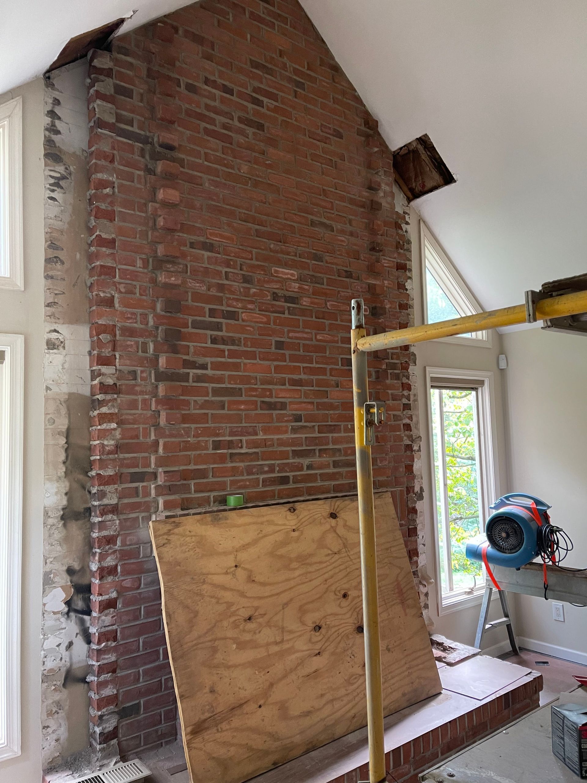 A large brick fireplace is being remodeled in a living room.