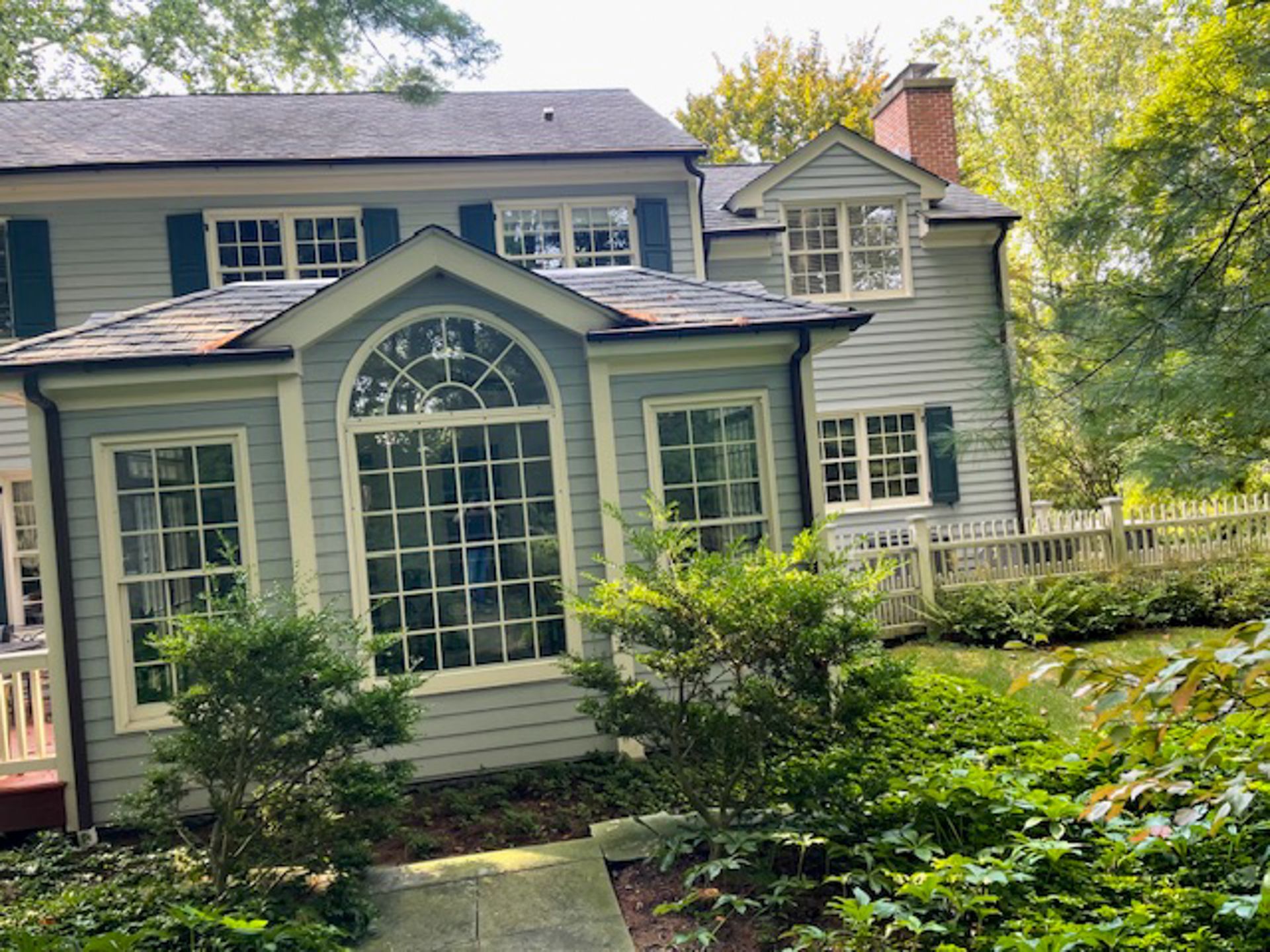 A large house with a lot of windows is surrounded by trees and bushes.