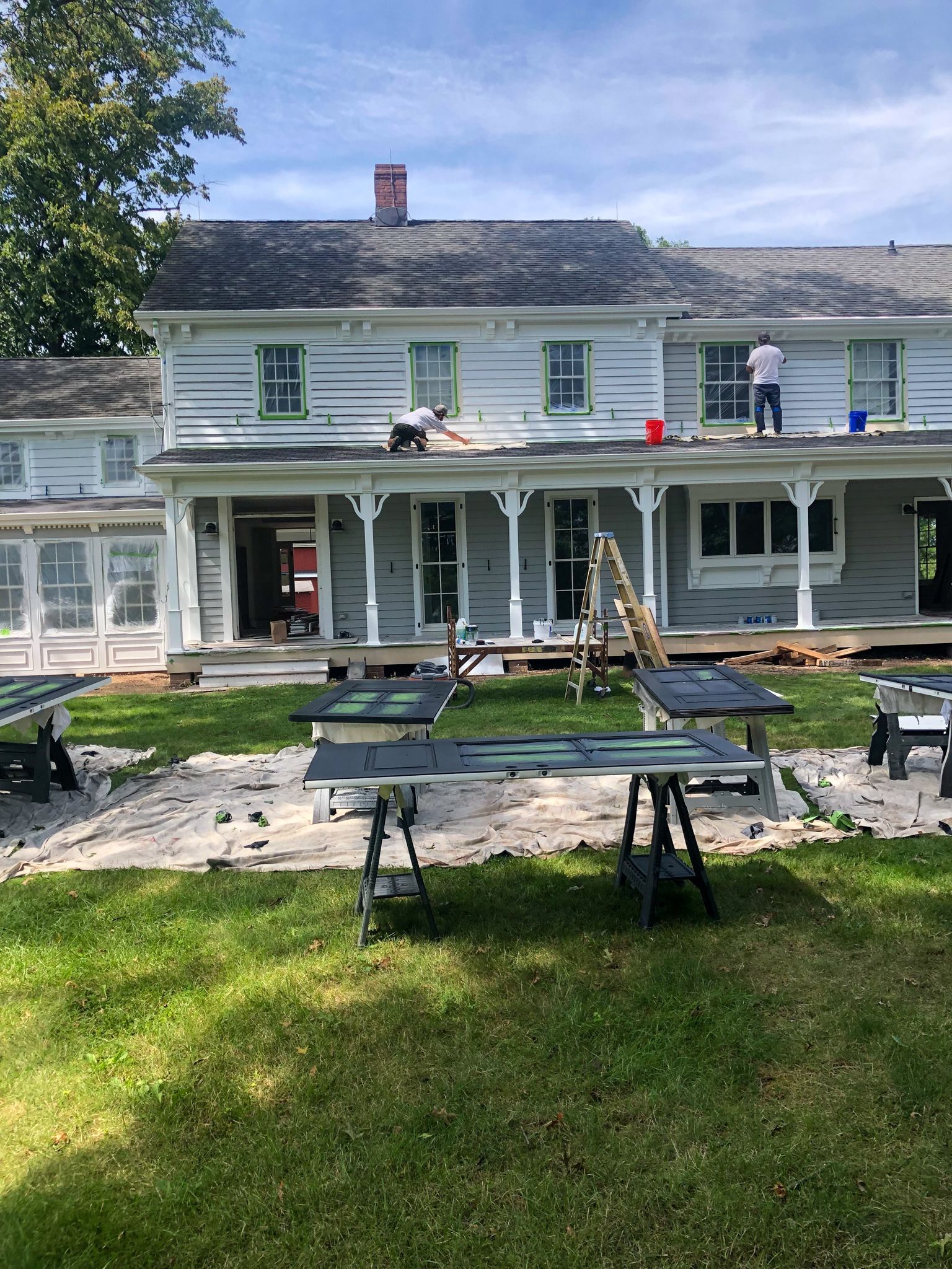 A man is painting the roof of a white house.
