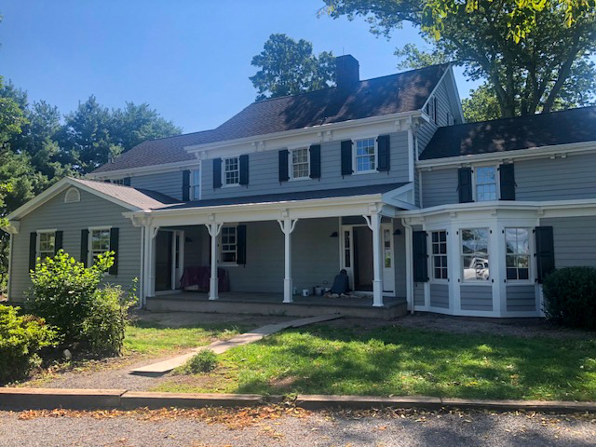A large house with a large porch and black shutters