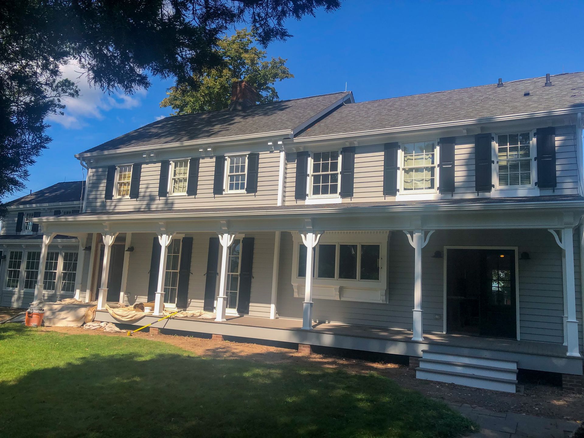 A large white house with black shutters and a large porch