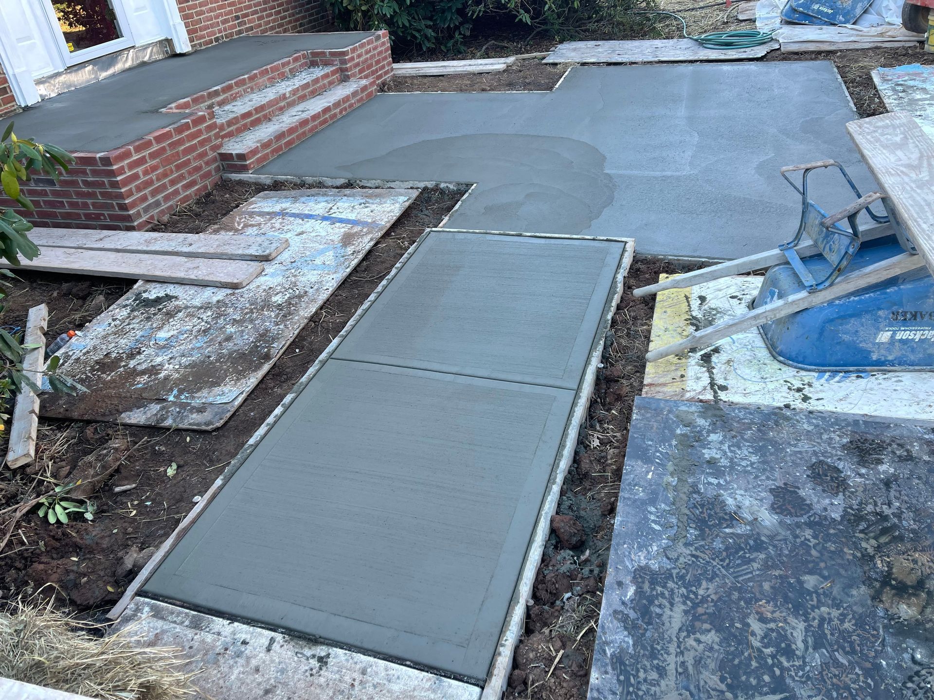 A concrete walkway is being built in front of a house.