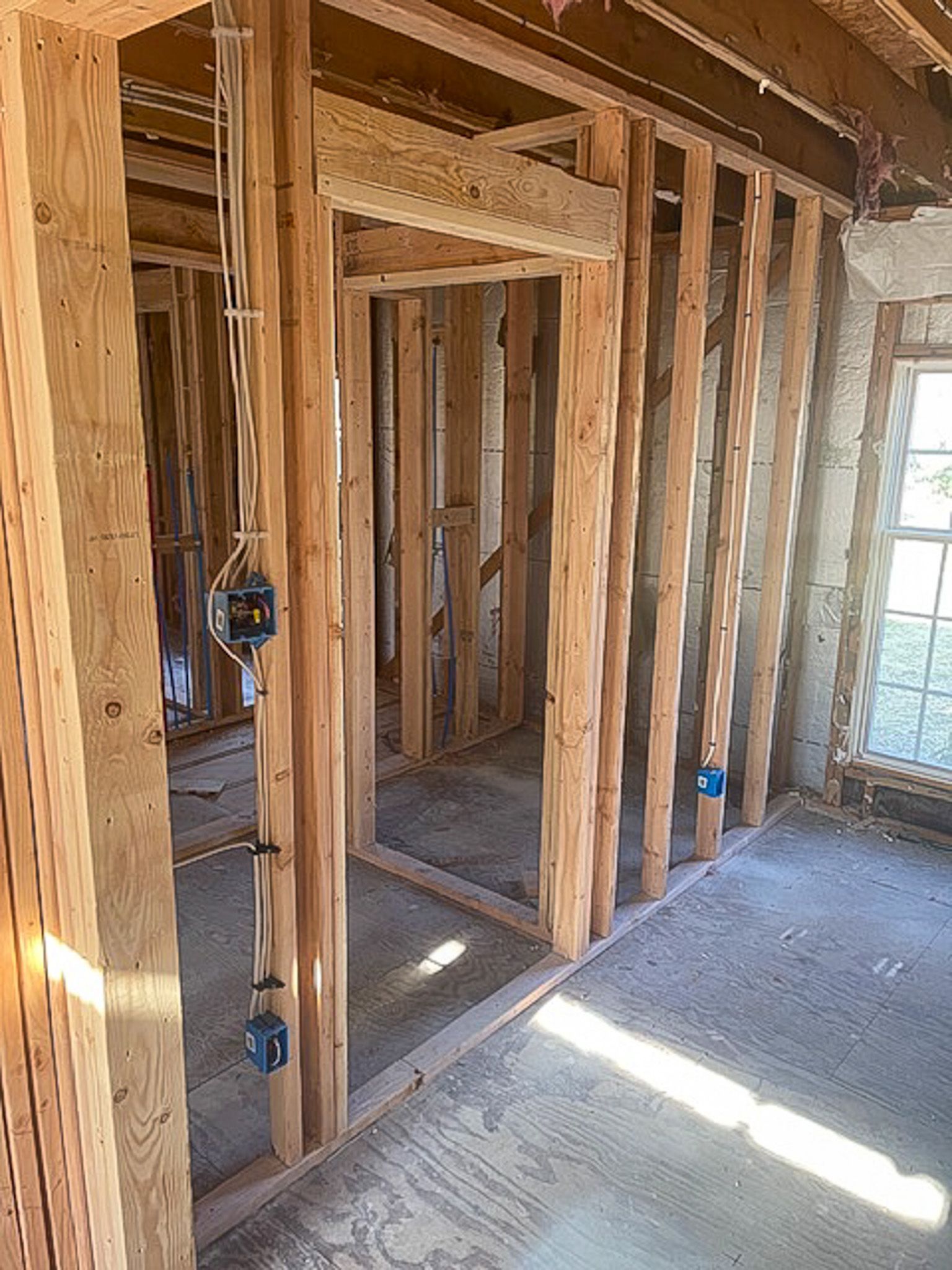 A room in a house under construction with wooden beams and a window.