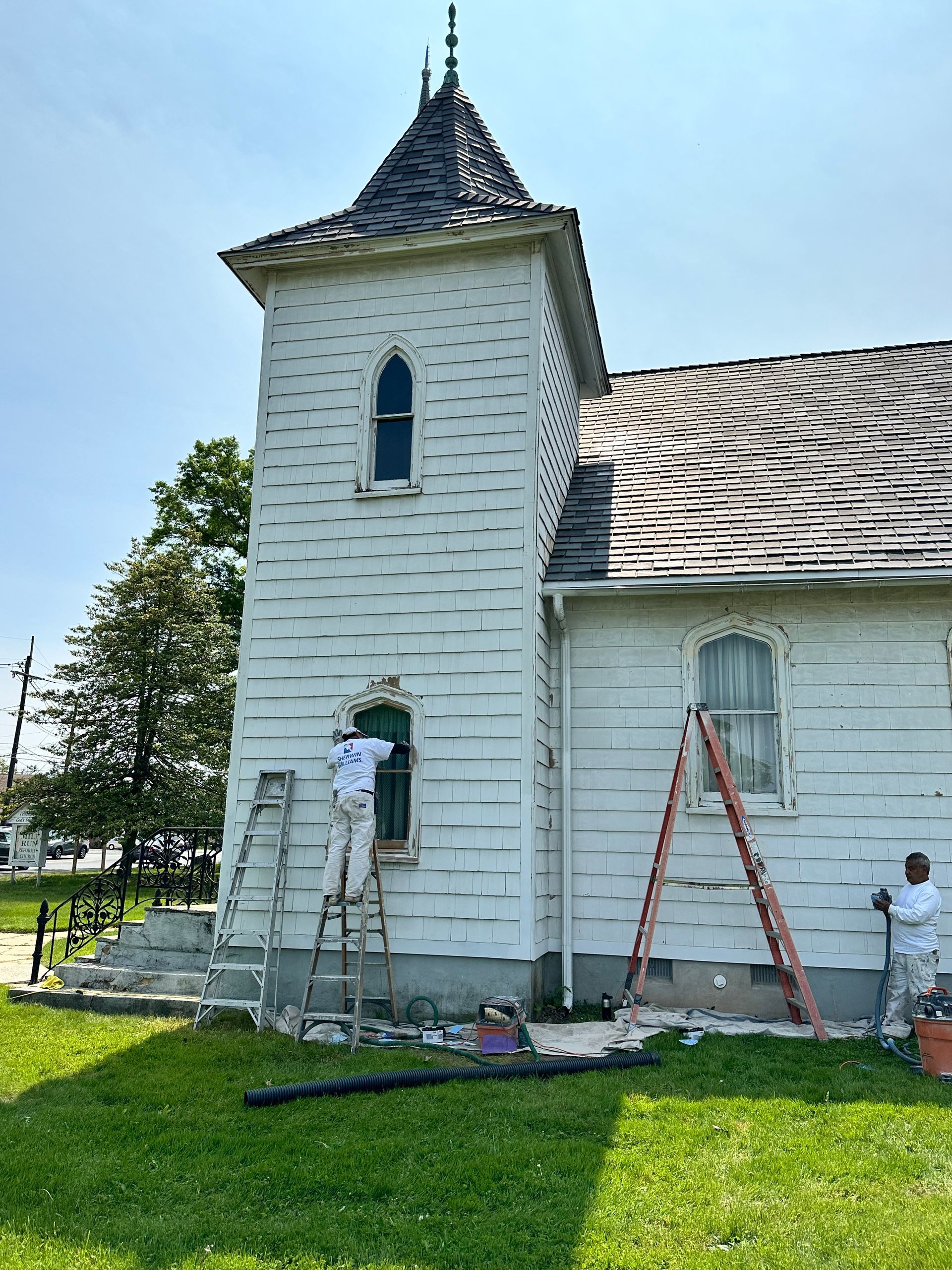A man is painting a window on the side of a building.