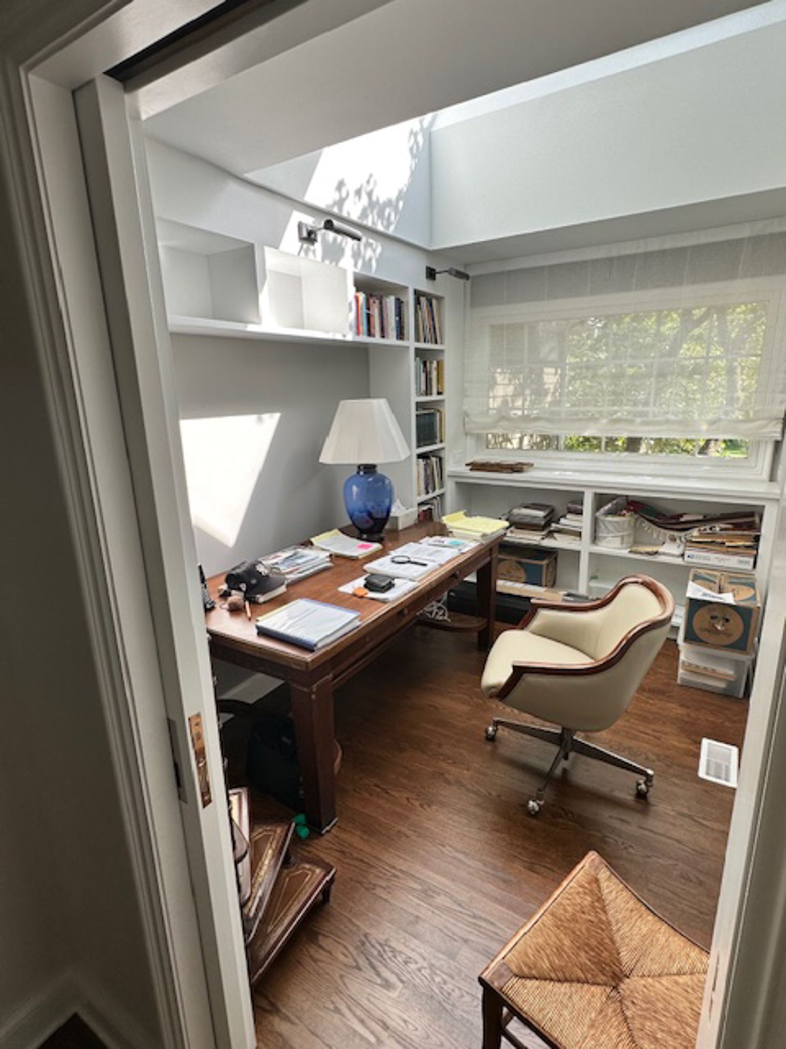 A home office with a desk , chair , lamp and shelves.