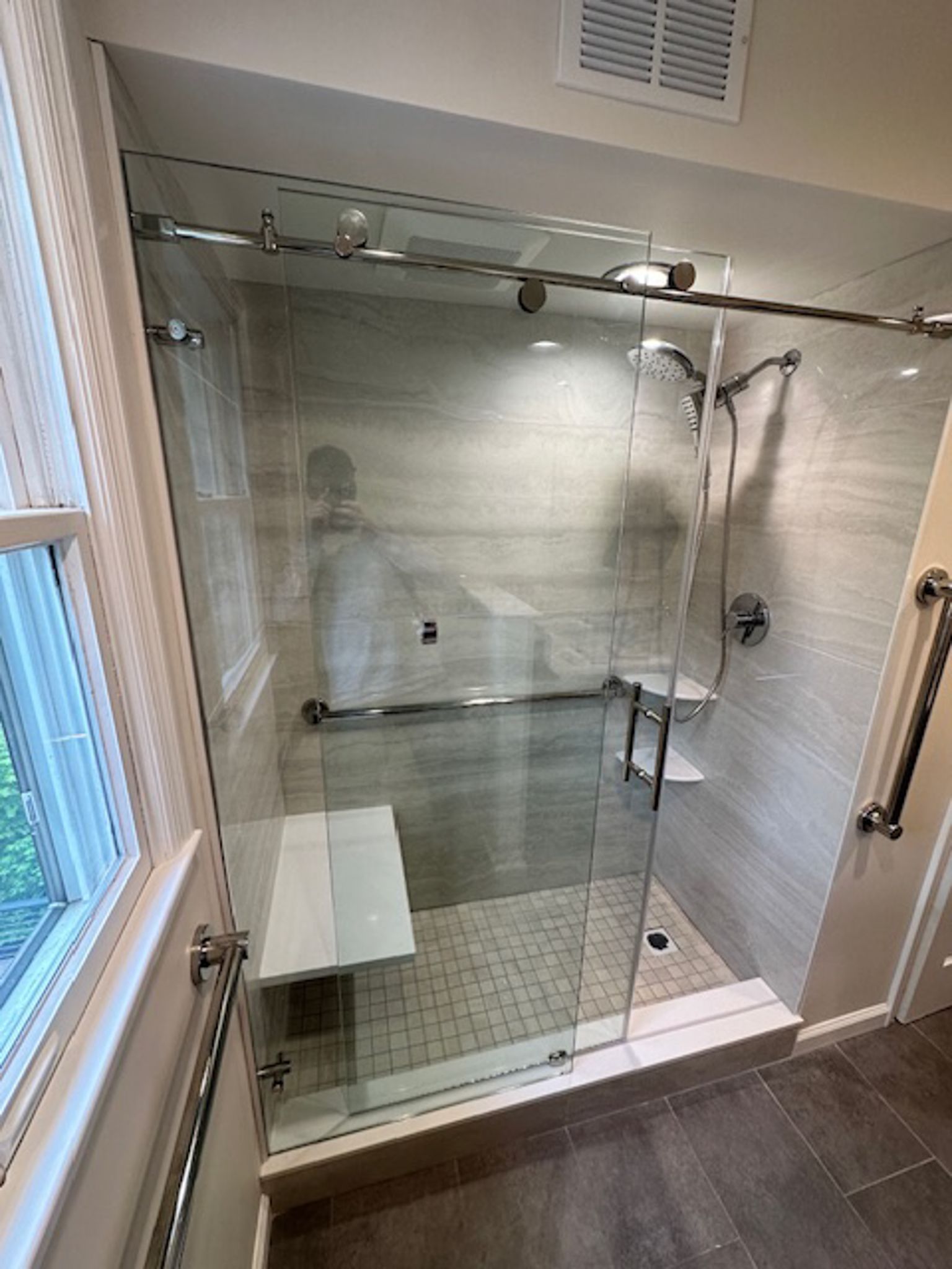 A bathroom with a sliding glass shower door and a bench.