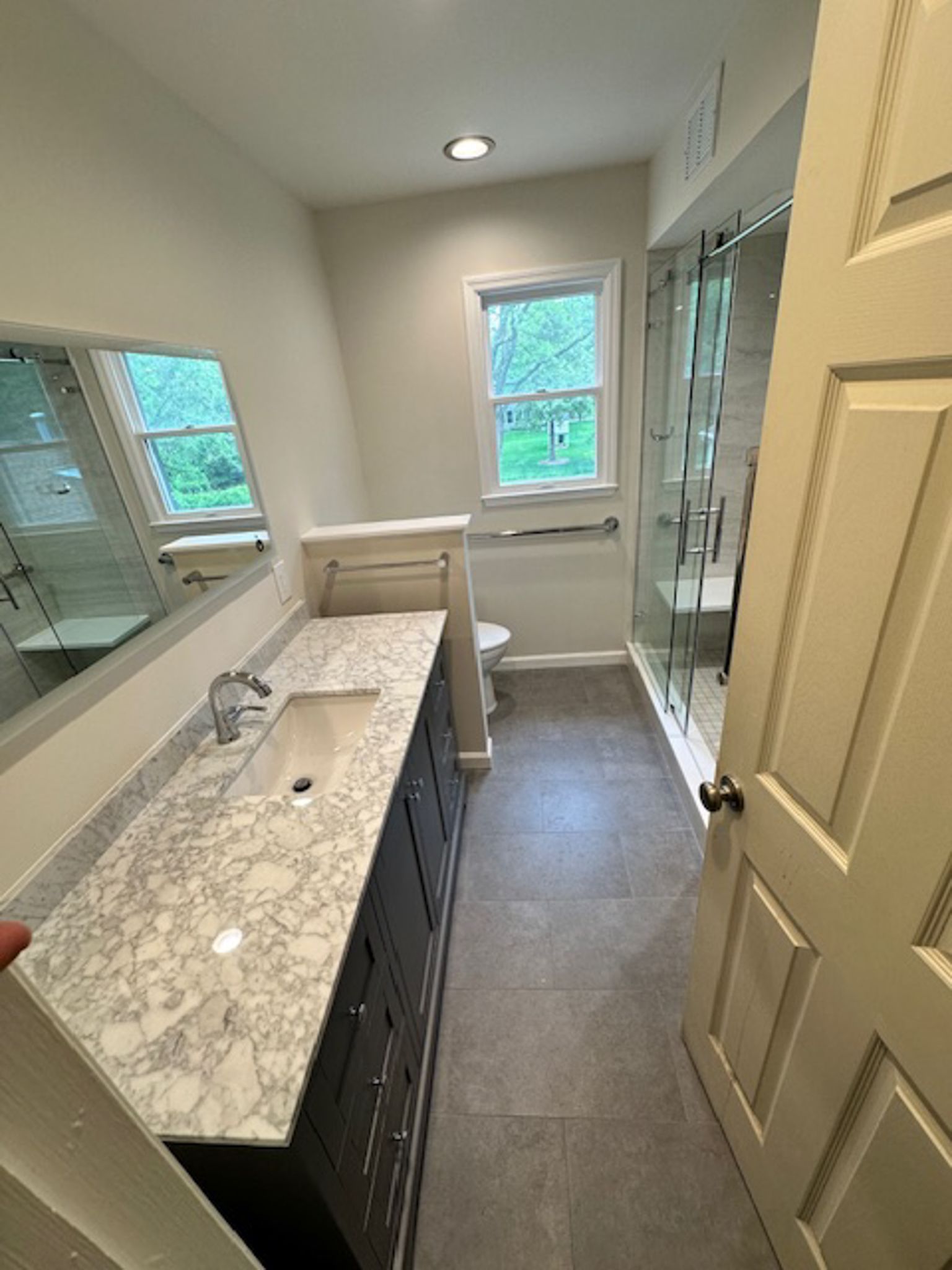 A bathroom with a sink , toilet , shower and mirror.