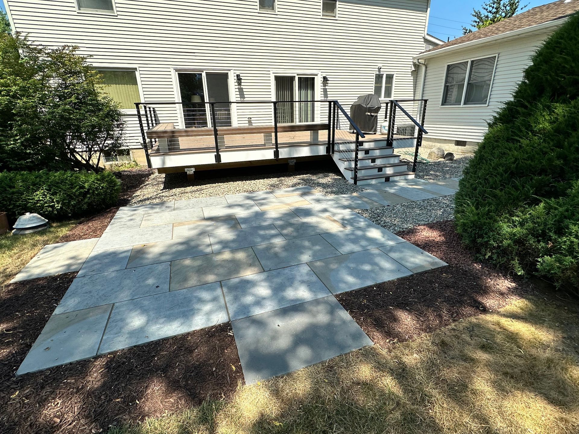 A patio with a deck and stairs in front of a house.