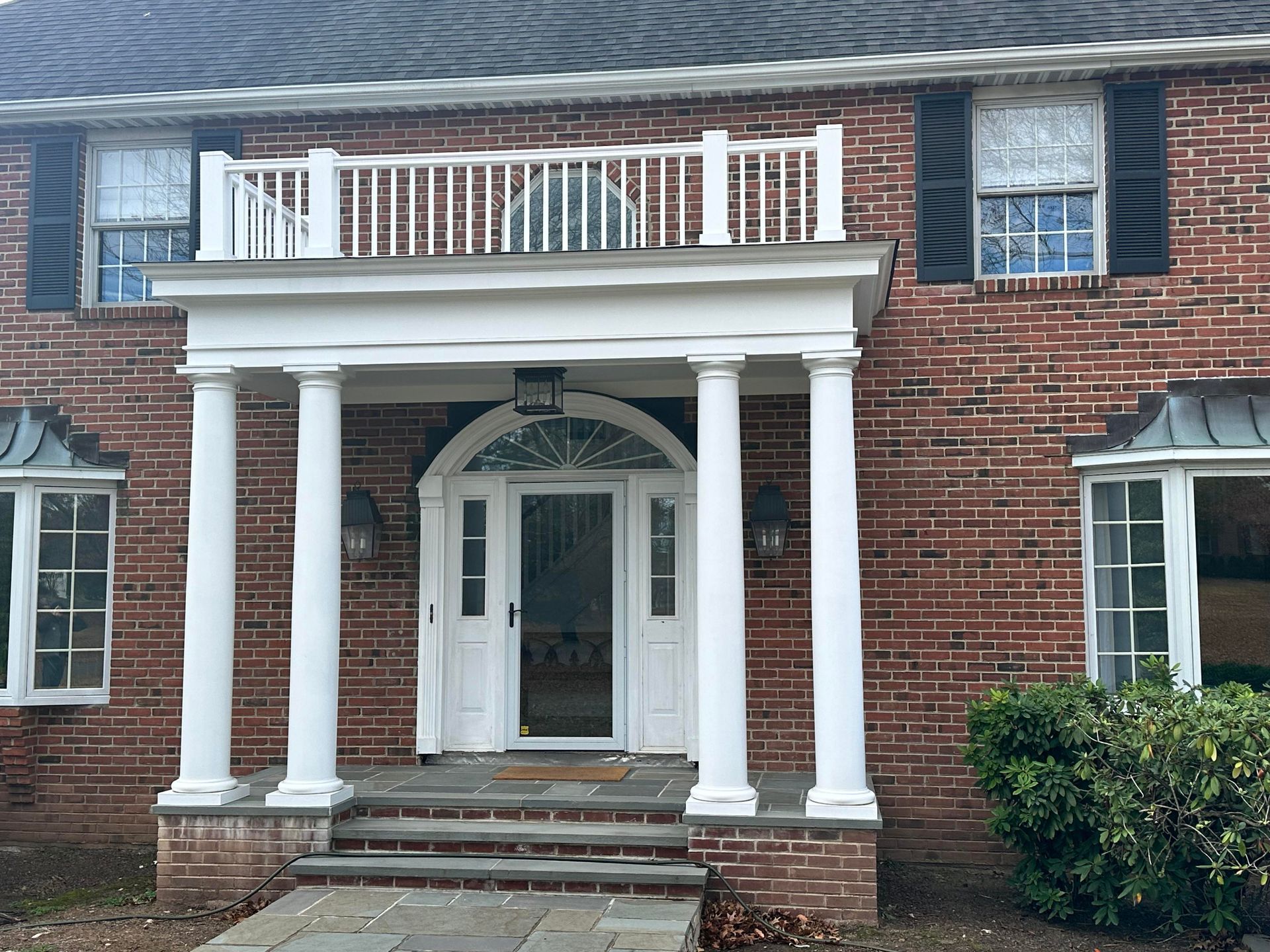 A brick house with white columns and a balcony